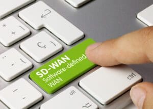 A keyboard with a green key labeled “SD-WAN” that a finger is touching.
