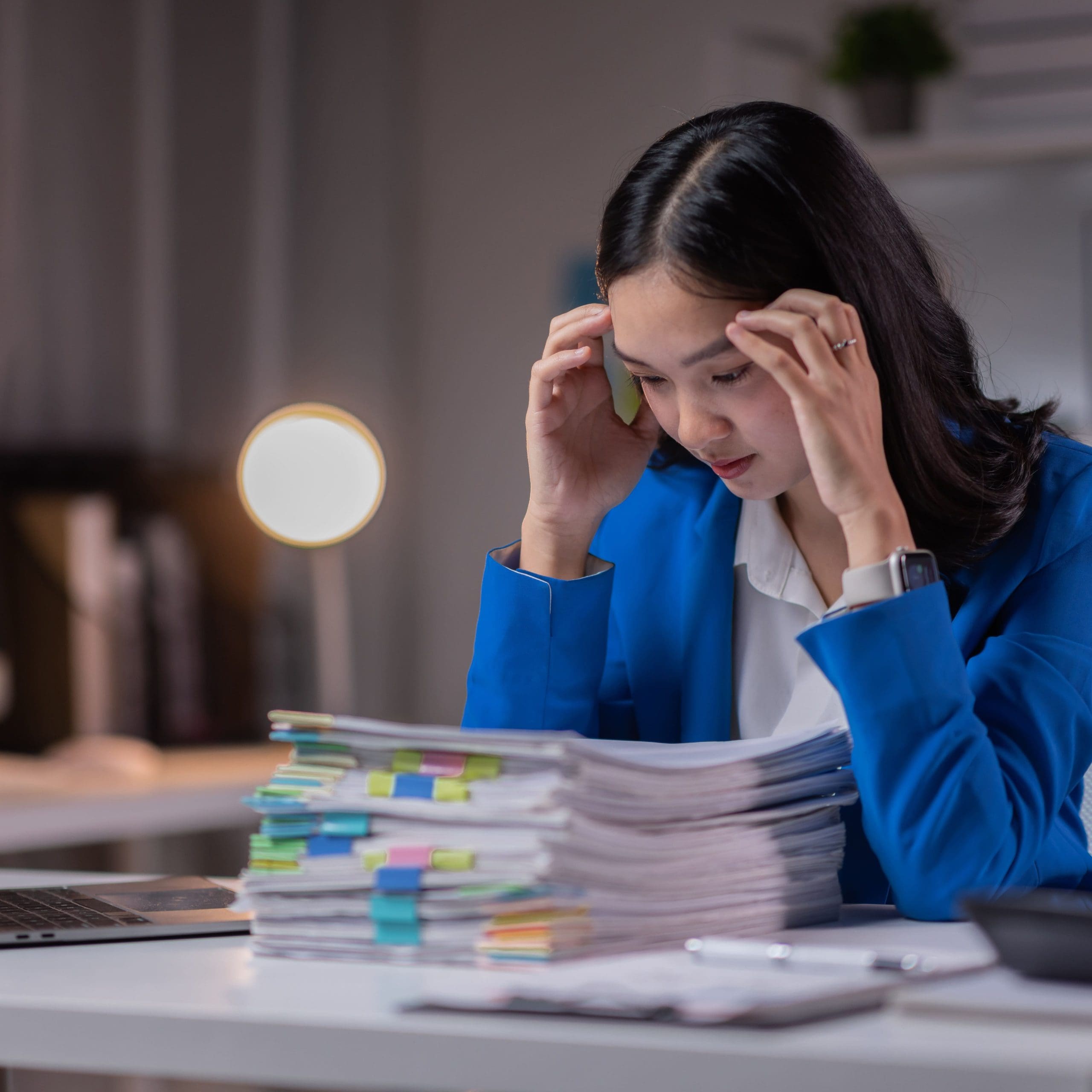 Portrait of Stressed business woman sitting and working hard at with front of computer and lots of documents on the table in workplace at late with serious action, Work hard and too late concept