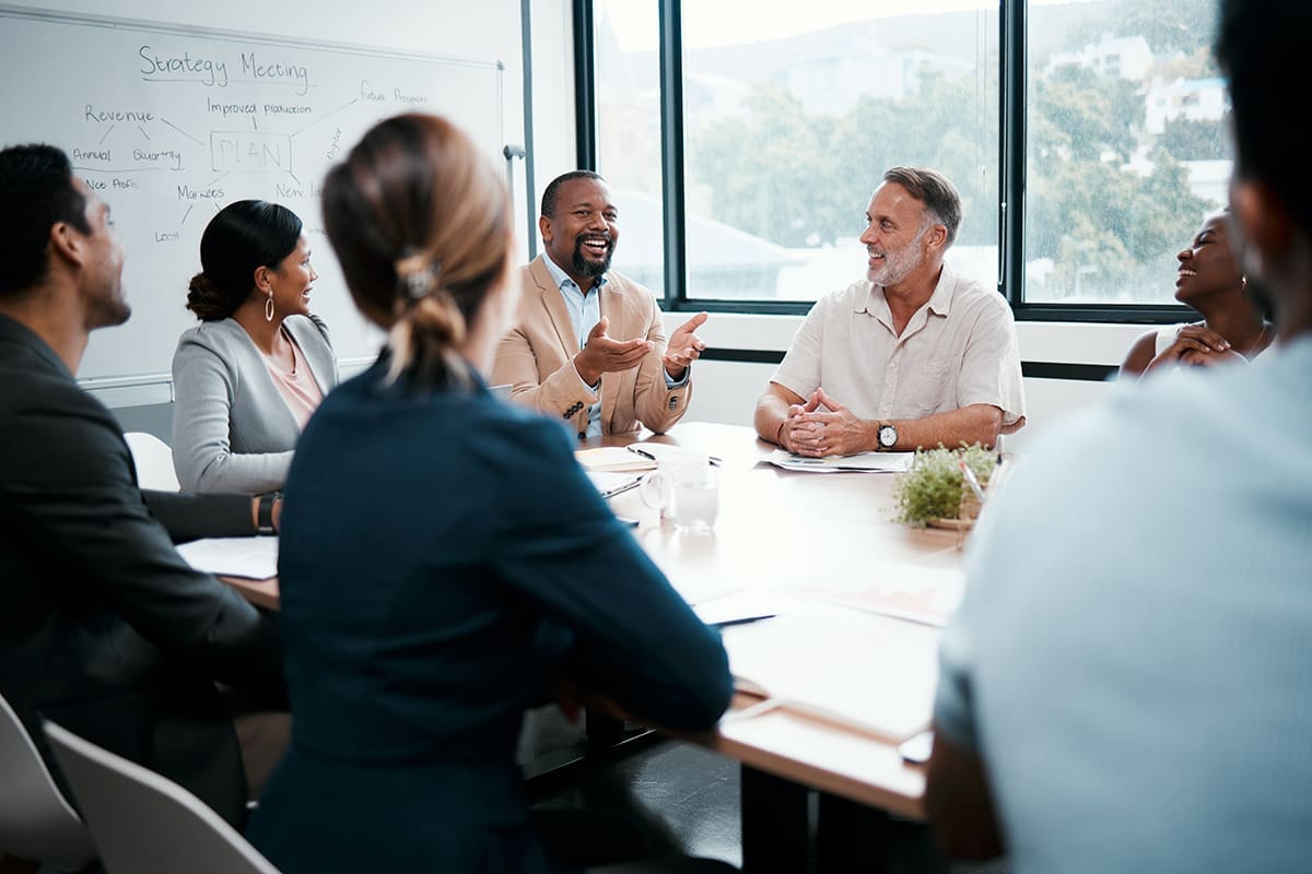 A group of people sitting around a table in a board room.