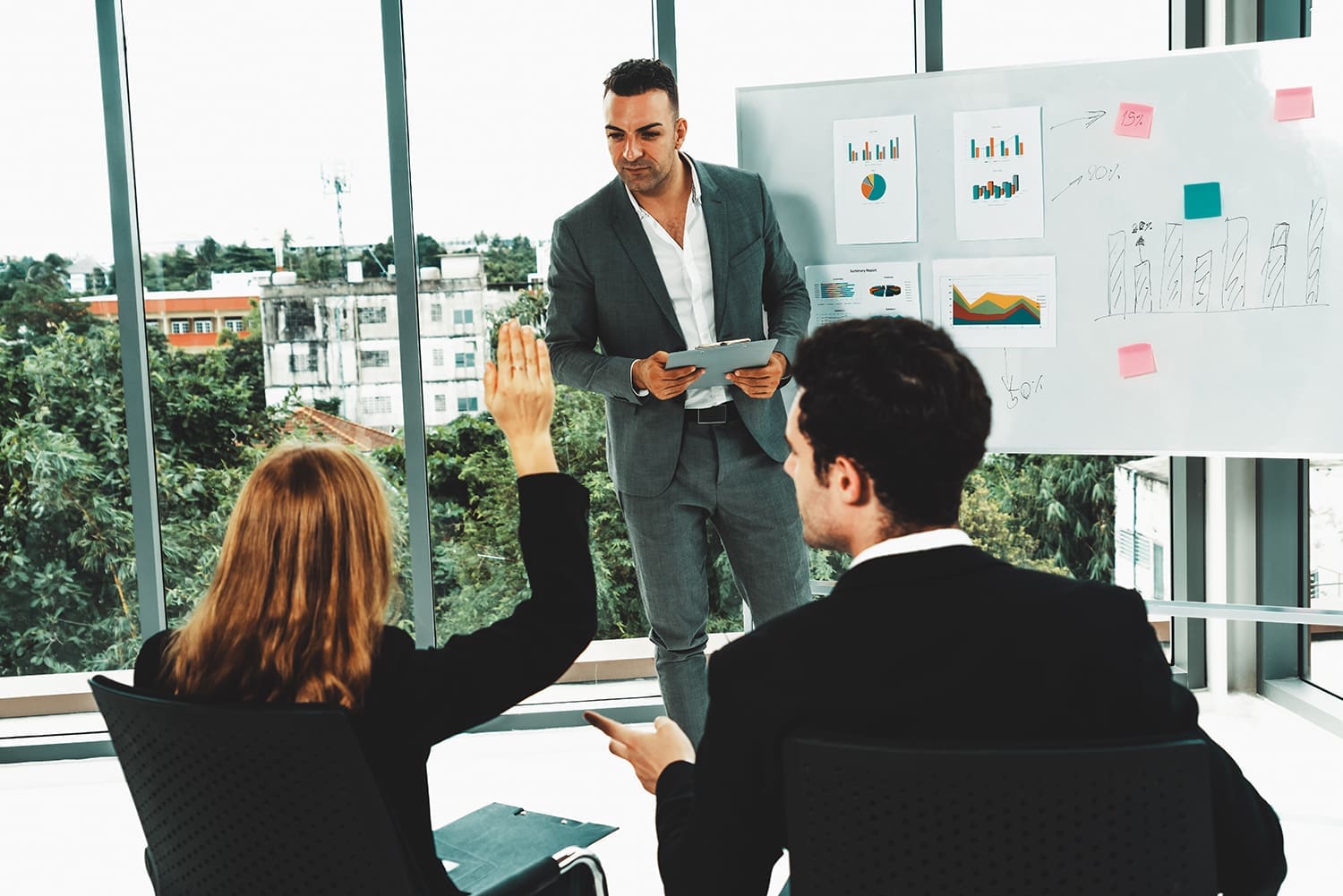 A businessperson stands in front of a whiteboard with a row of bank executives watching his presentation.